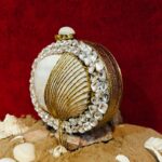 Angle view of Rhinestone-Embellished Bag Shell Encircling the White Clam Seashell with Tassel Chain